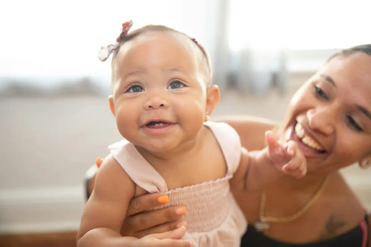 A smiling baby held up by a parent