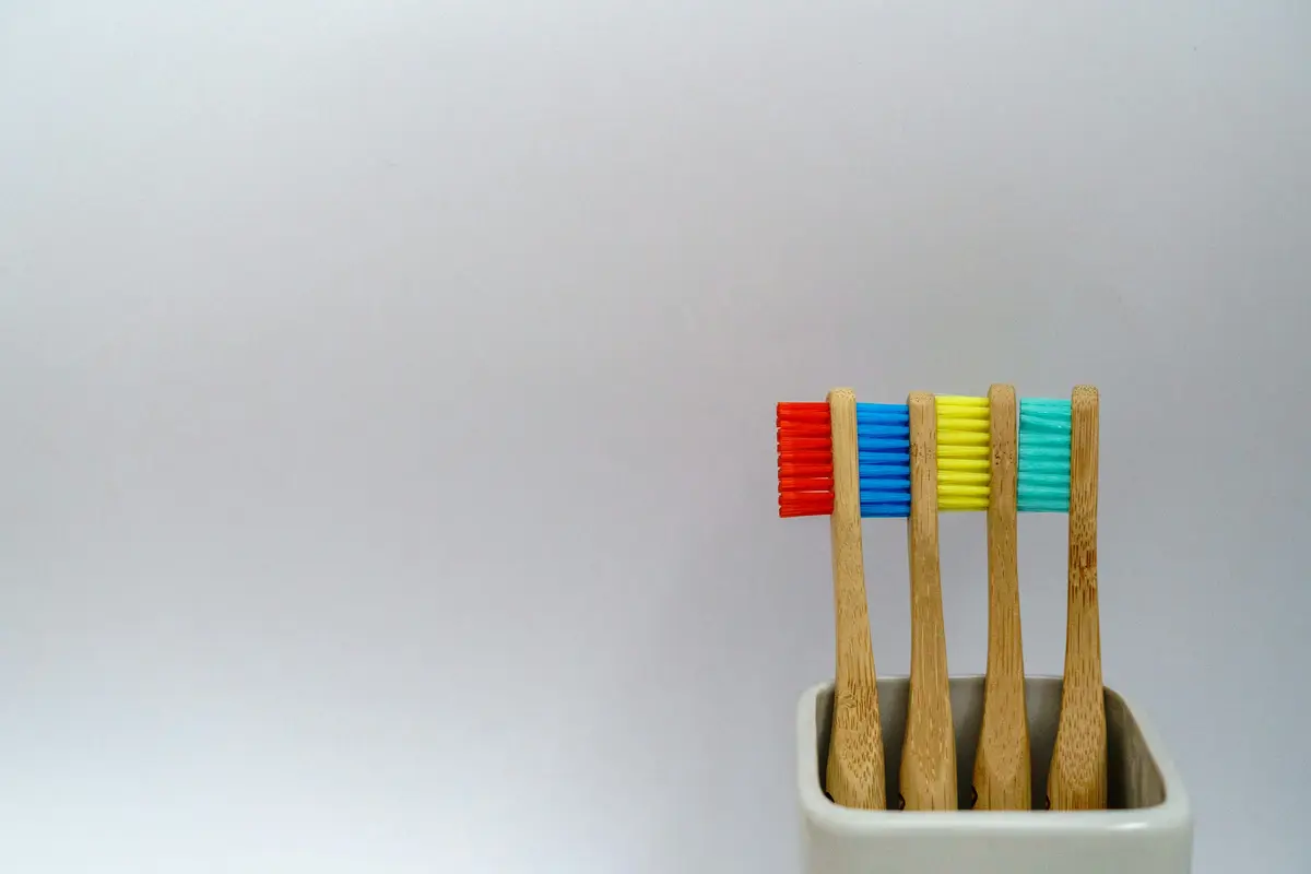 Bamboo toothbrushes with colored bristles in a cup