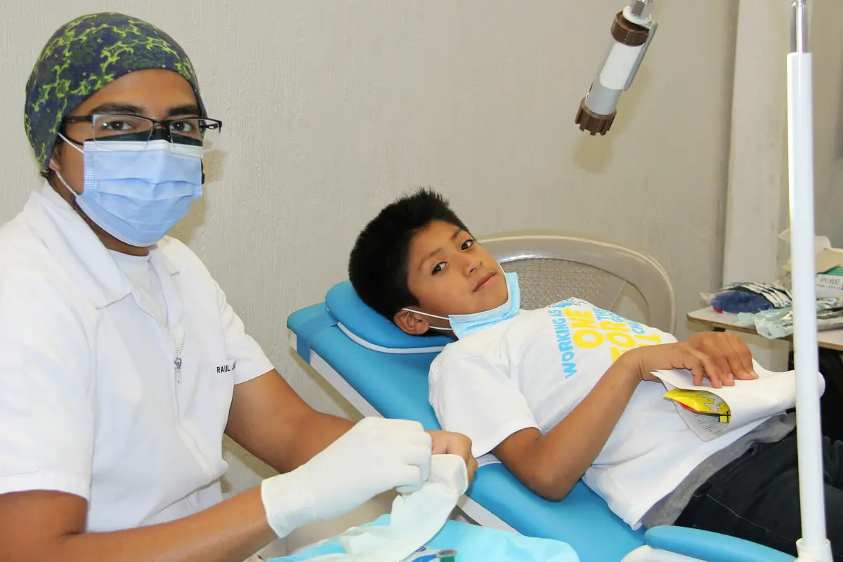 A young boy resting in a dental chair next to the dentist