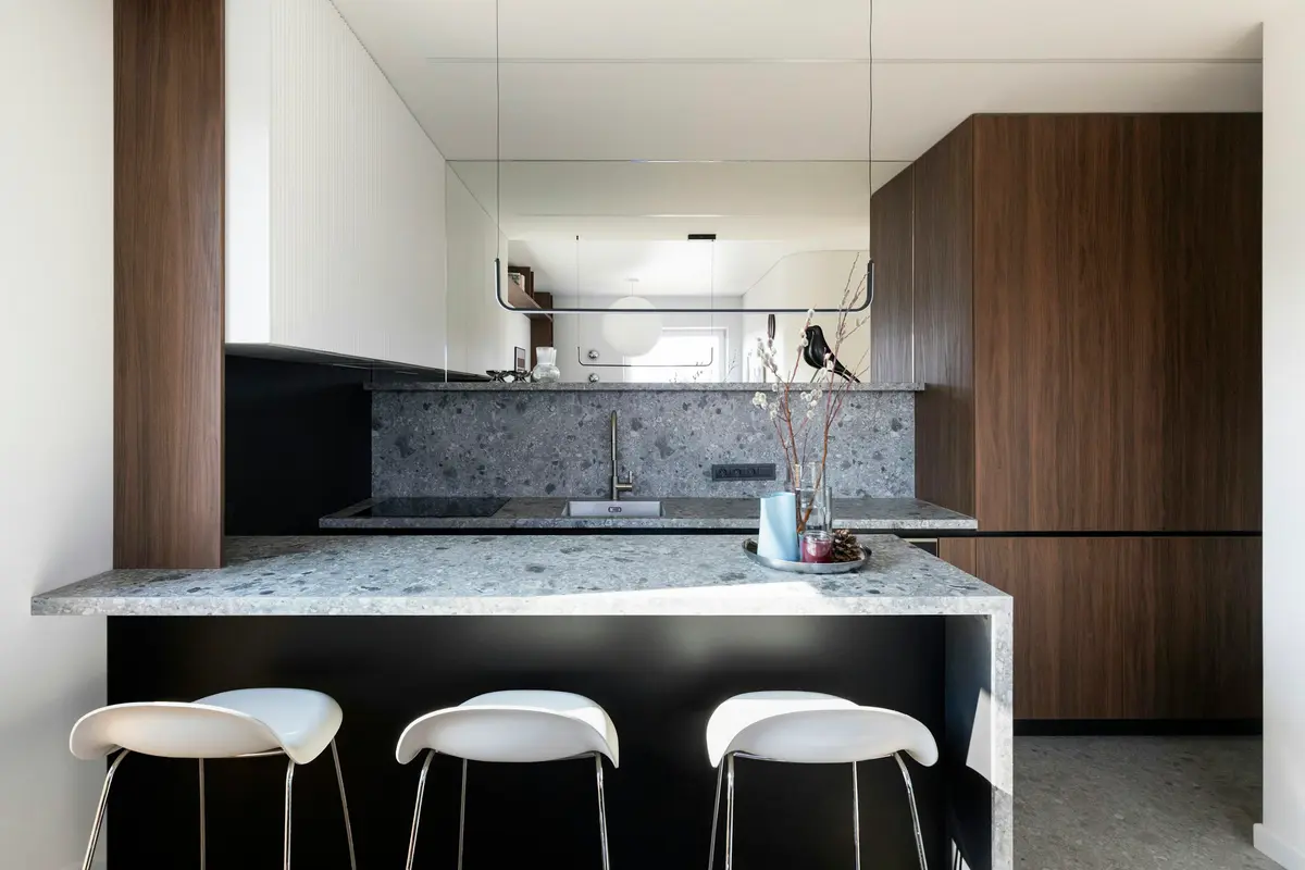 Walnut kitchen with a stone counter and white stools