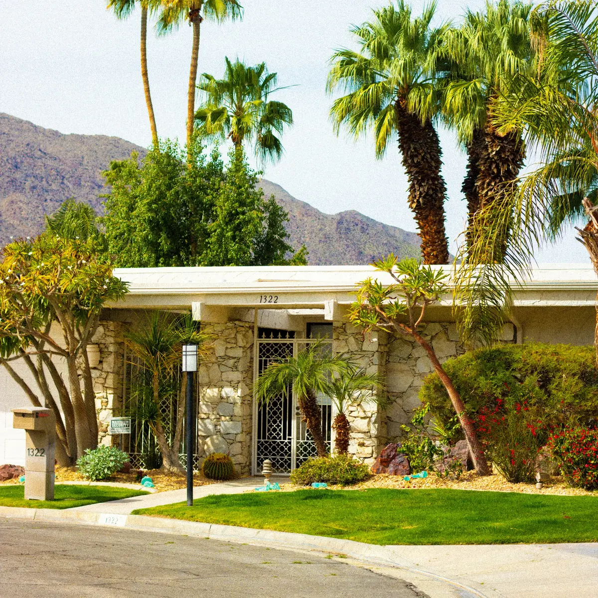 A low white house with stone walls under palm trees