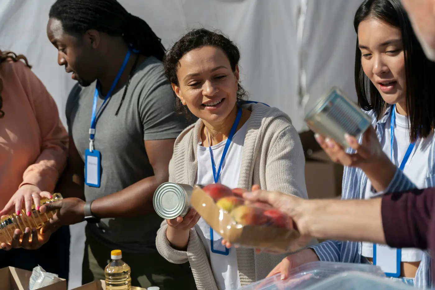 Volunteers with name badges handing out canned food and apples