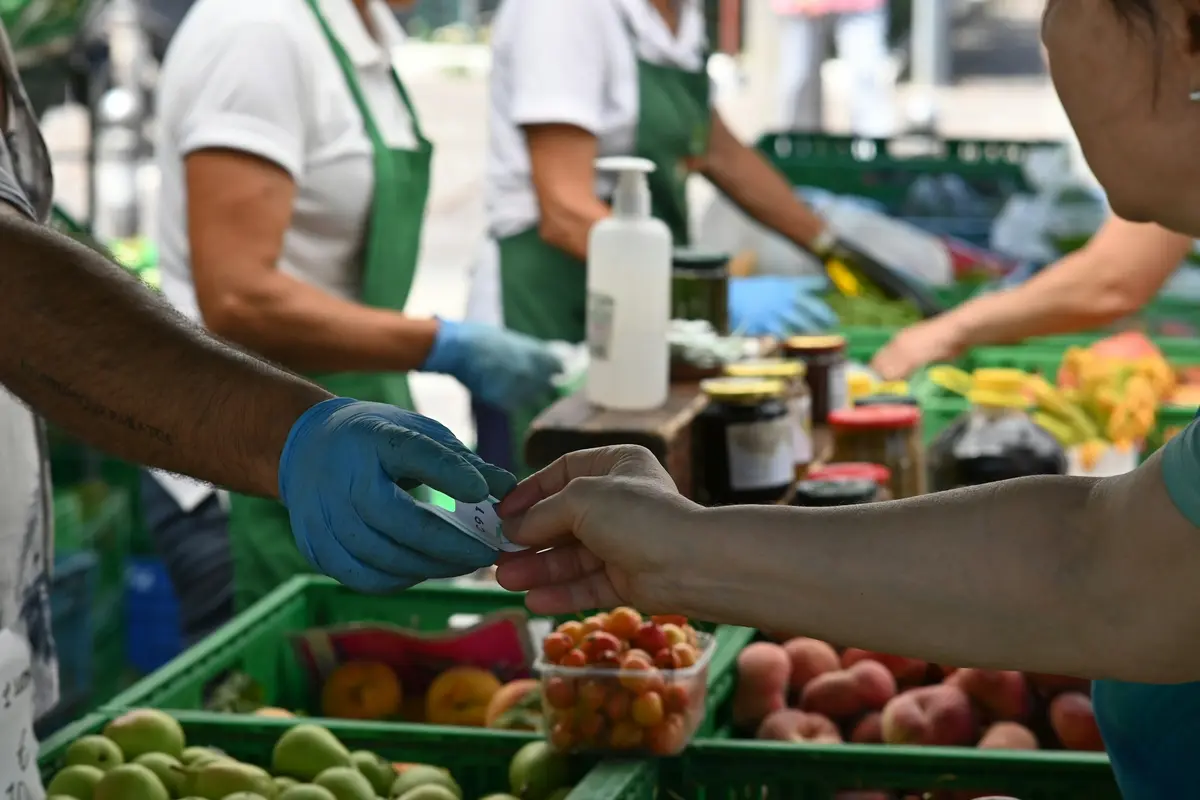 Hands passing fruit across a table stacked with produce crates