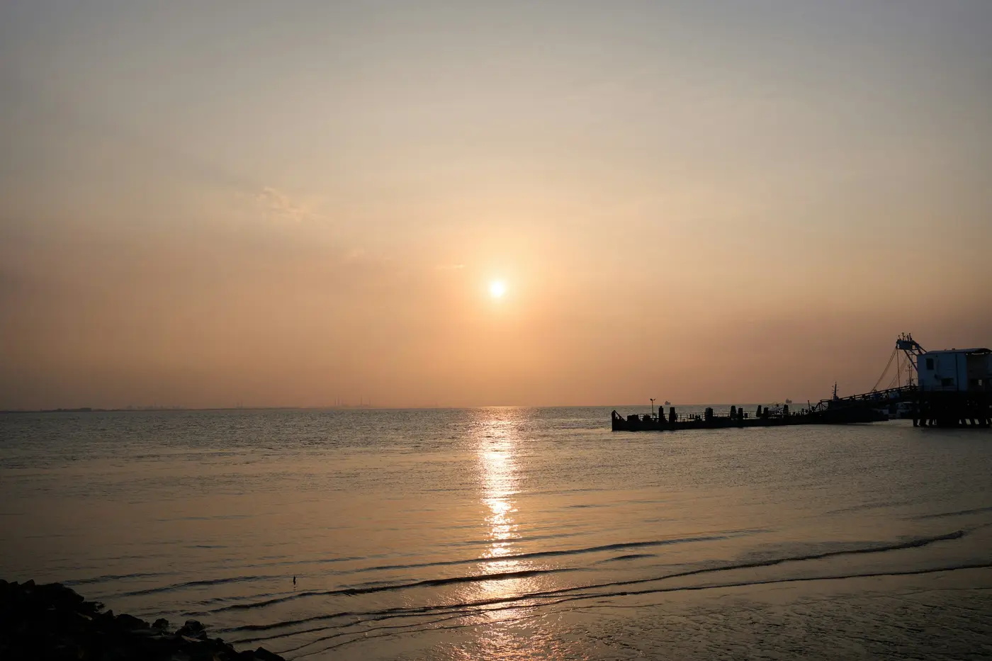 The sun setting over the ocean beside a pier