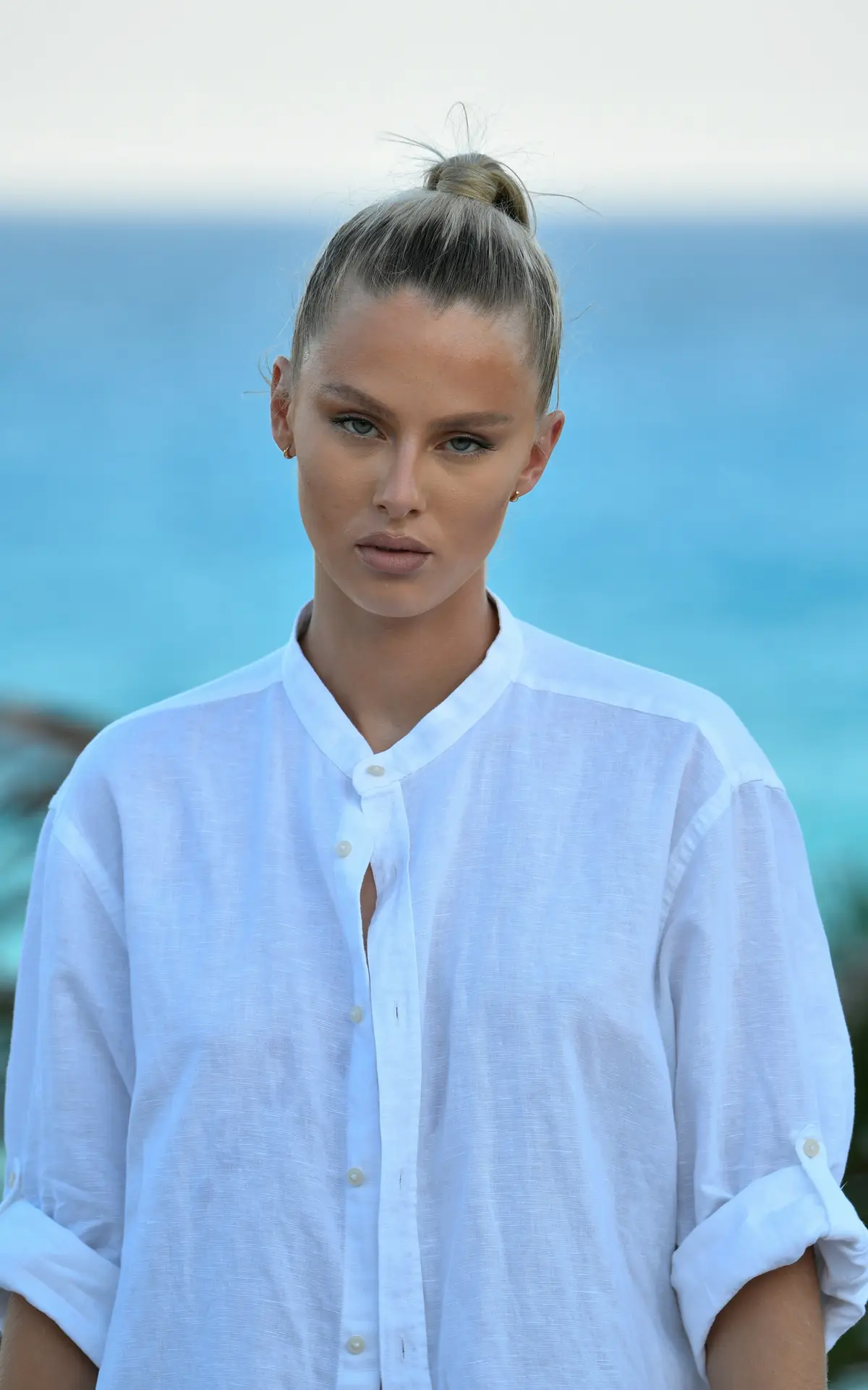 A woman in a white linen shirt by the ocean