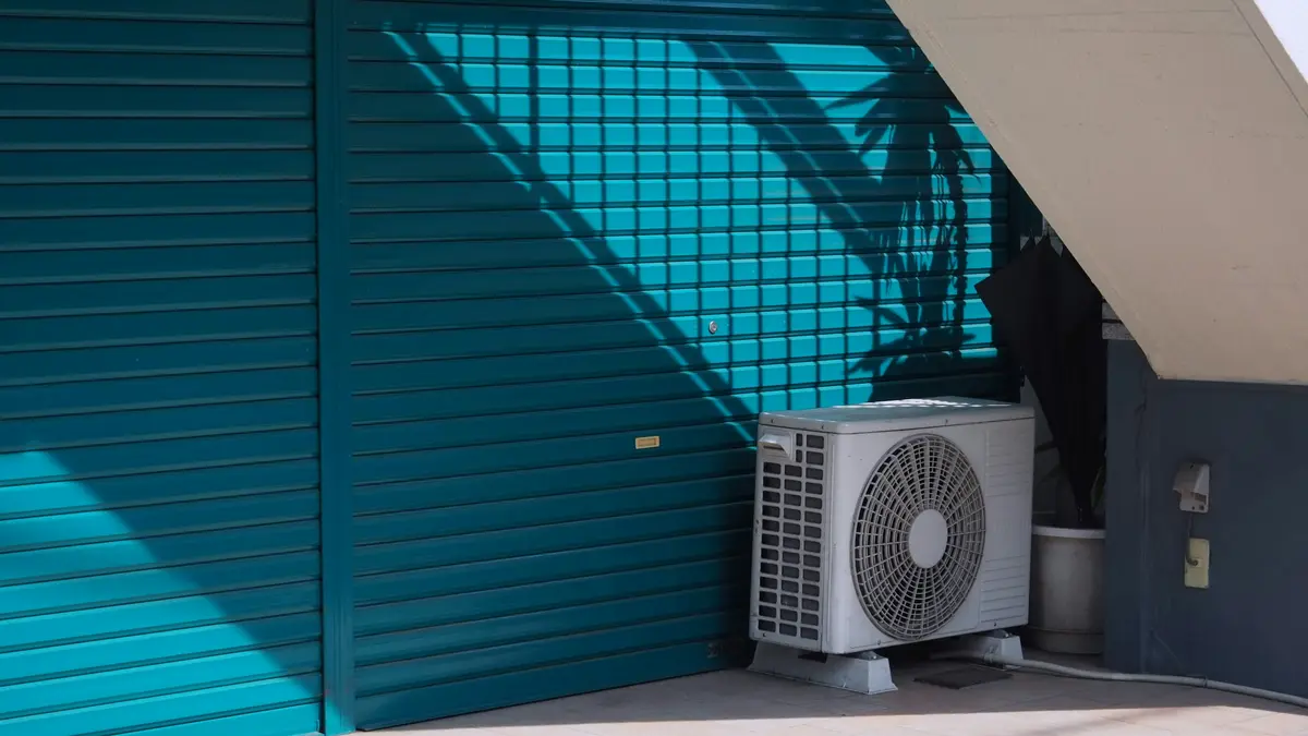 An outdoor AC unit against teal window shutters