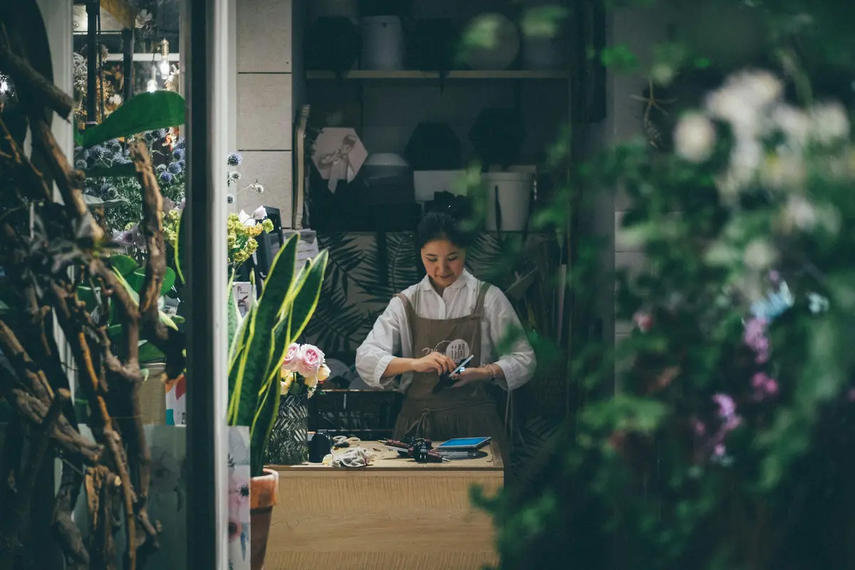A florist working at the counter of a plant-filled shop