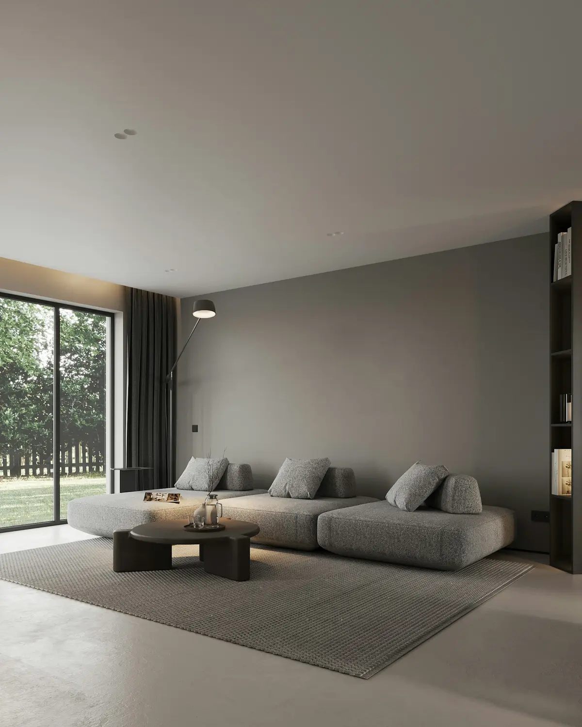 A grey living room with a long low sofa and a large empty wall