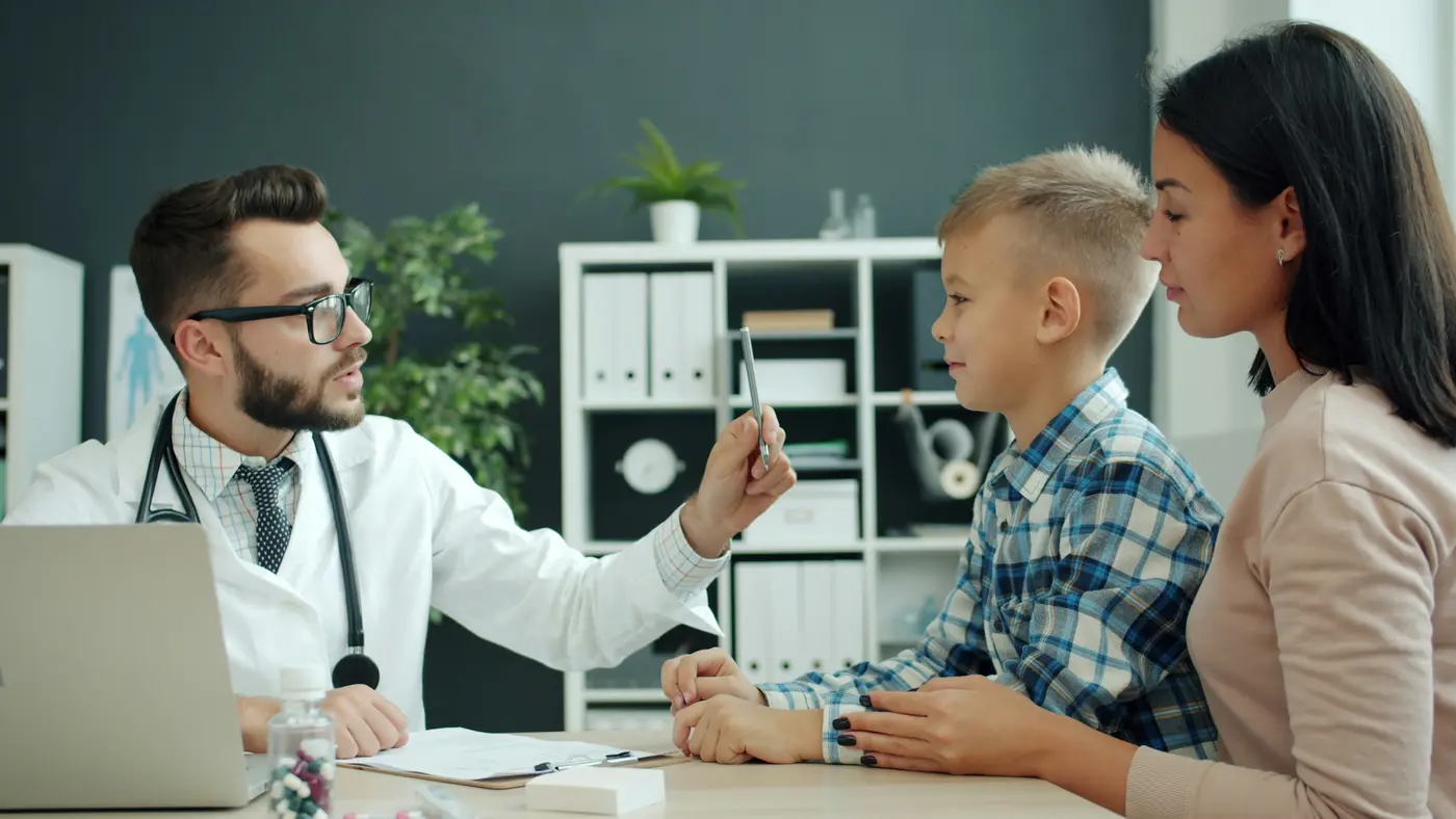 A doctor talks with a boy and his mother during a checkup
