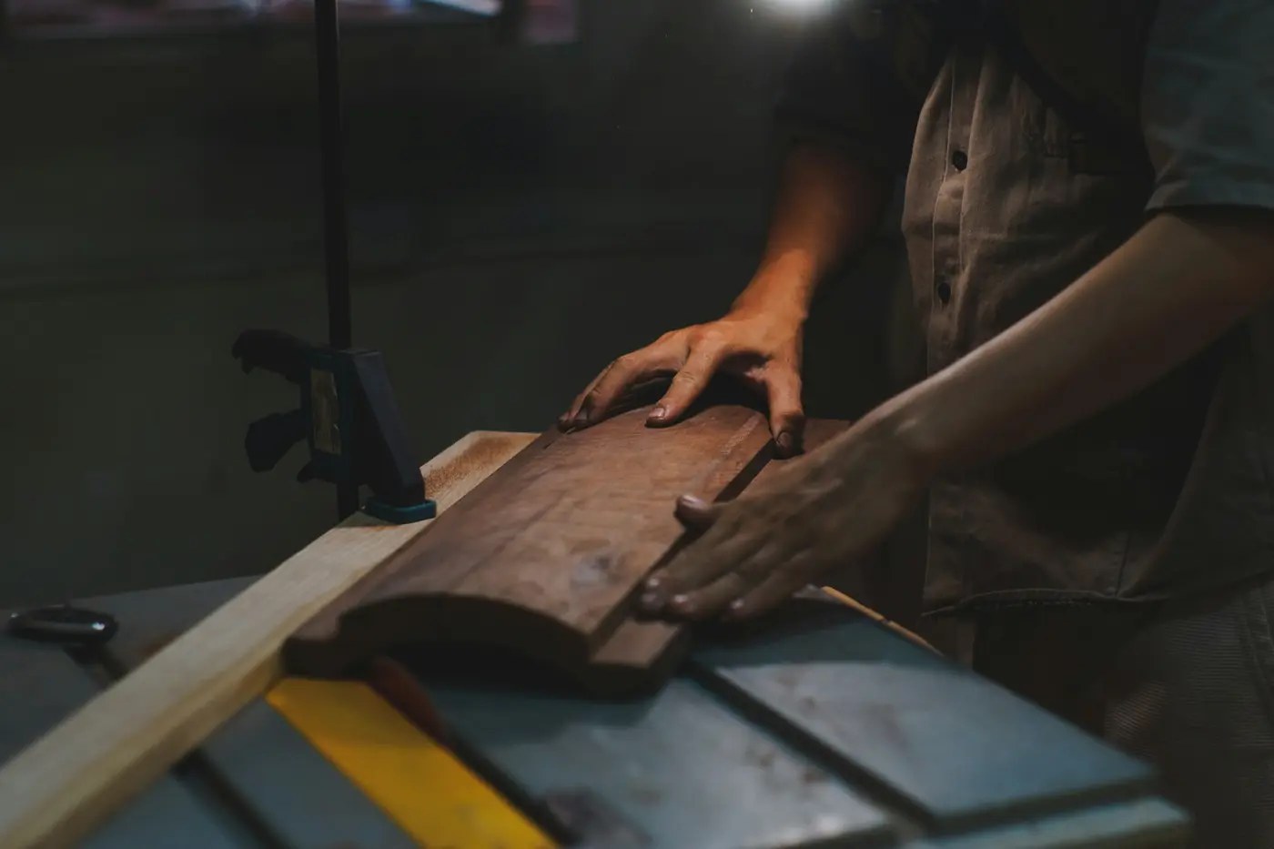 Hands guiding a plank of walnut across a workbench