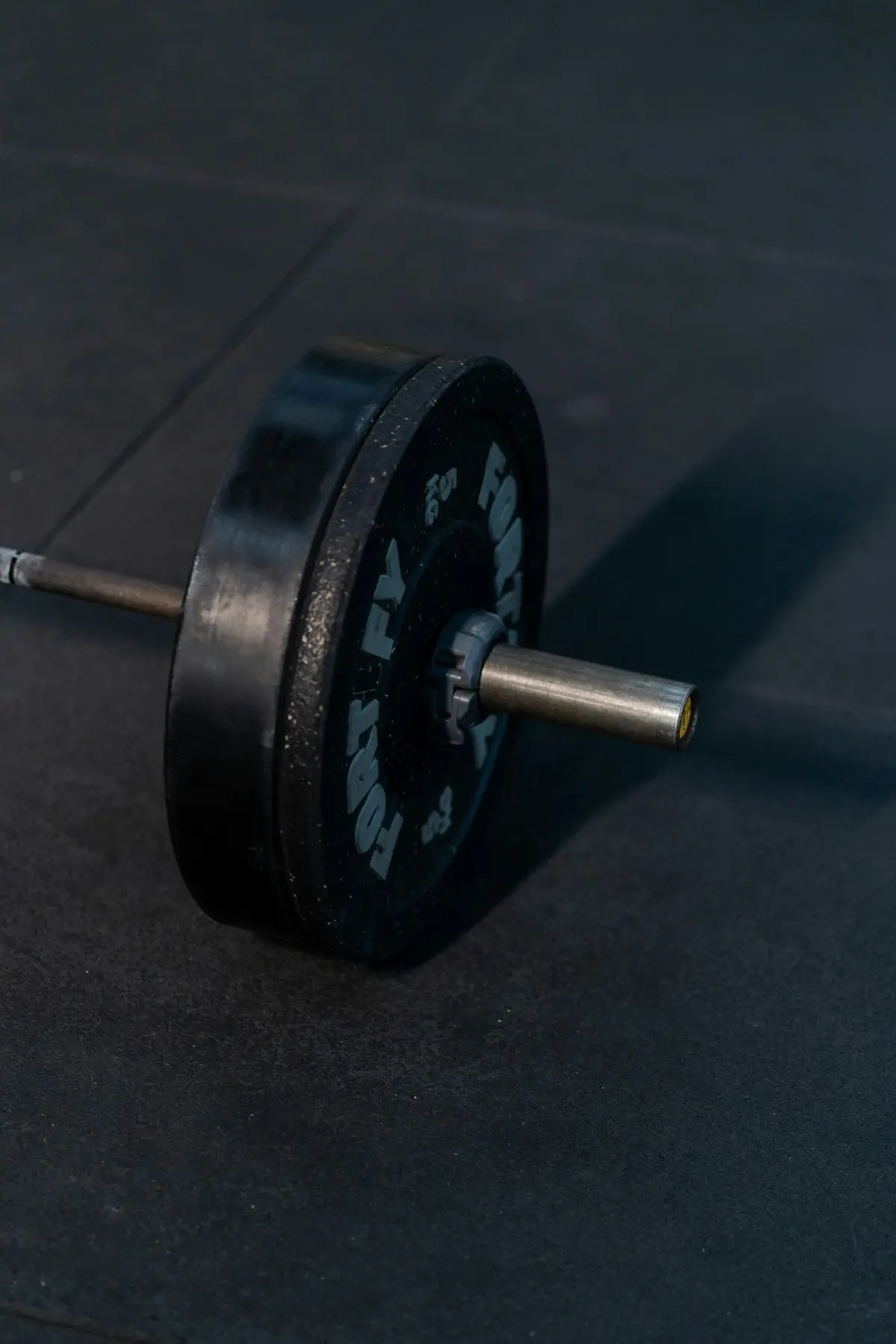 A barbell with black plates on a dark gym floor