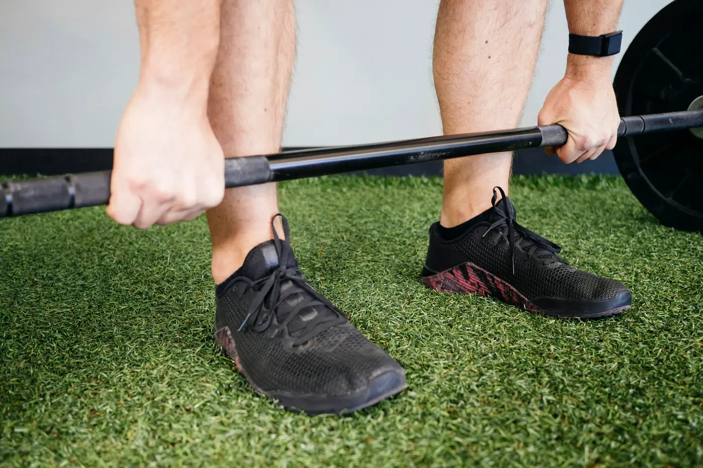 Hands gripping a barbell on turf before a lift