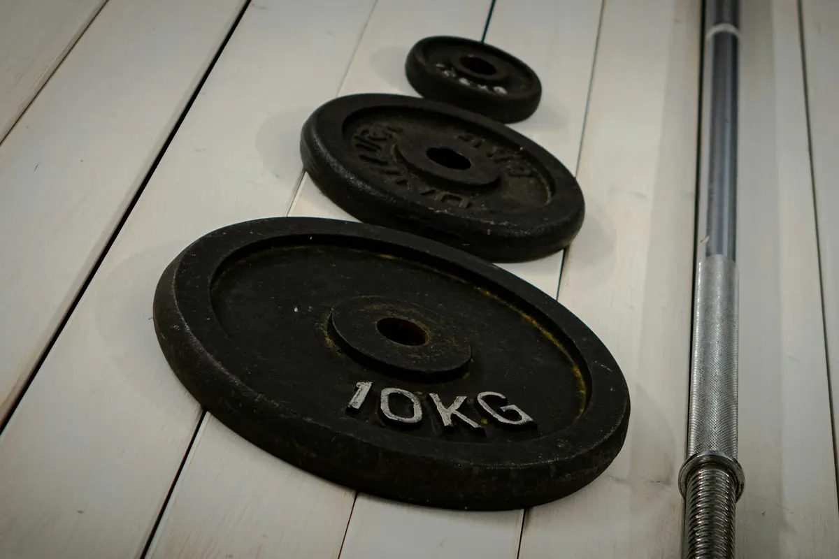 Iron weight plates and a bar on a wooden floor