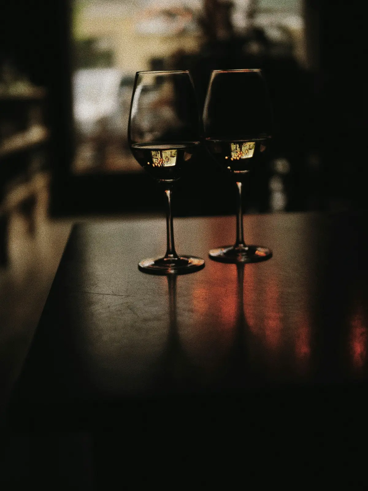 Two glasses of red wine on a dark table