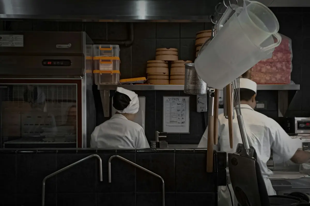 Two cooks in white working at a tiled ramen kitchen