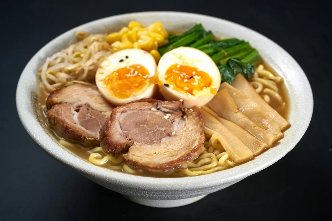 A bowl of tonkotsu ramen with pork, soft eggs, corn and bamboo shoots