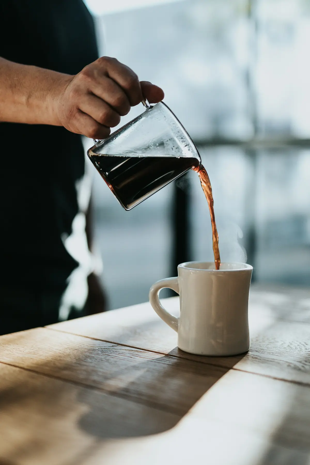 Coffee poured from a glass carafe into a white mug
