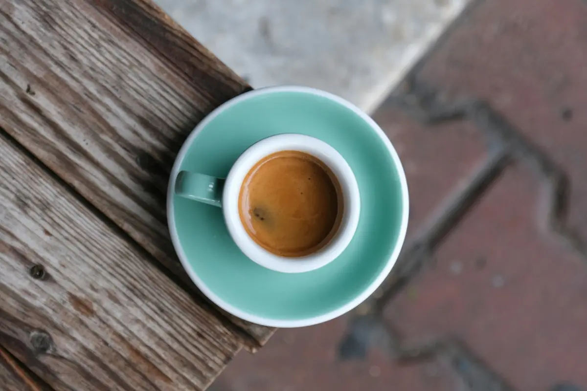 An espresso in a teal cup on a wooden table