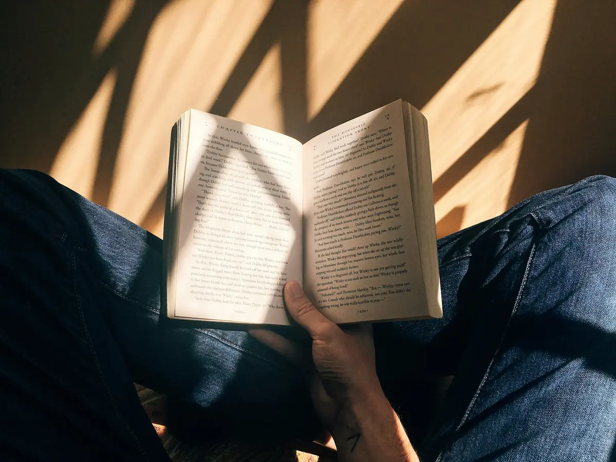 An open paperback held up in a patch of afternoon sun