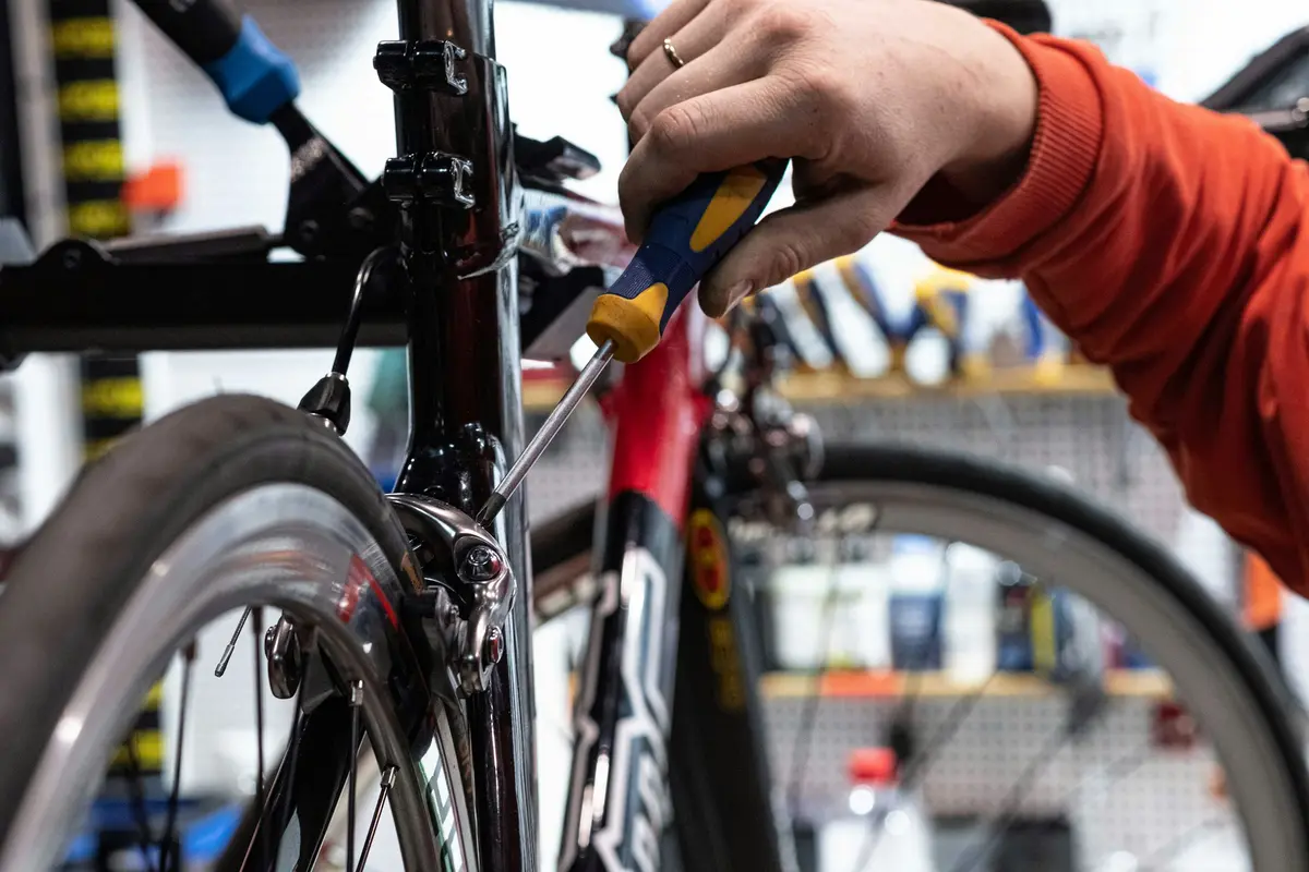 A mechanic adjusting the front brake of a bike in a workstand