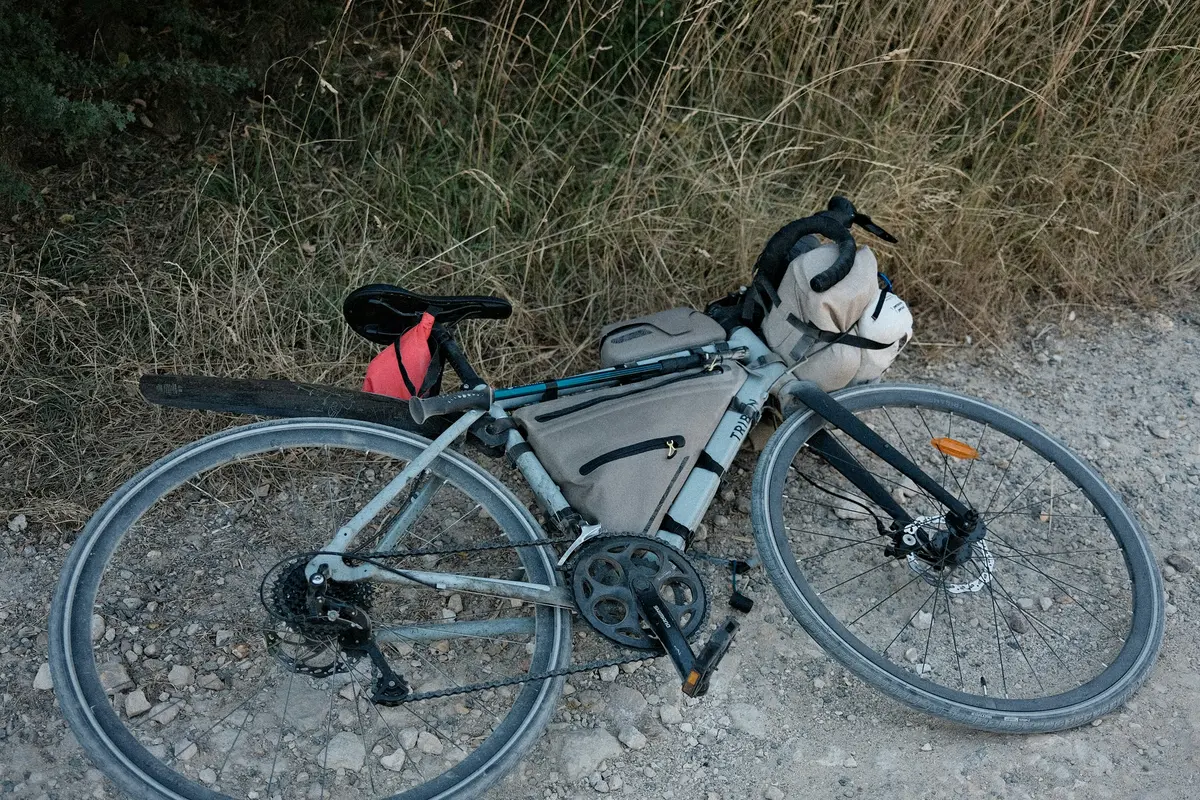 A loaded touring bike with frame and saddle bags lying on a gravel shoulder