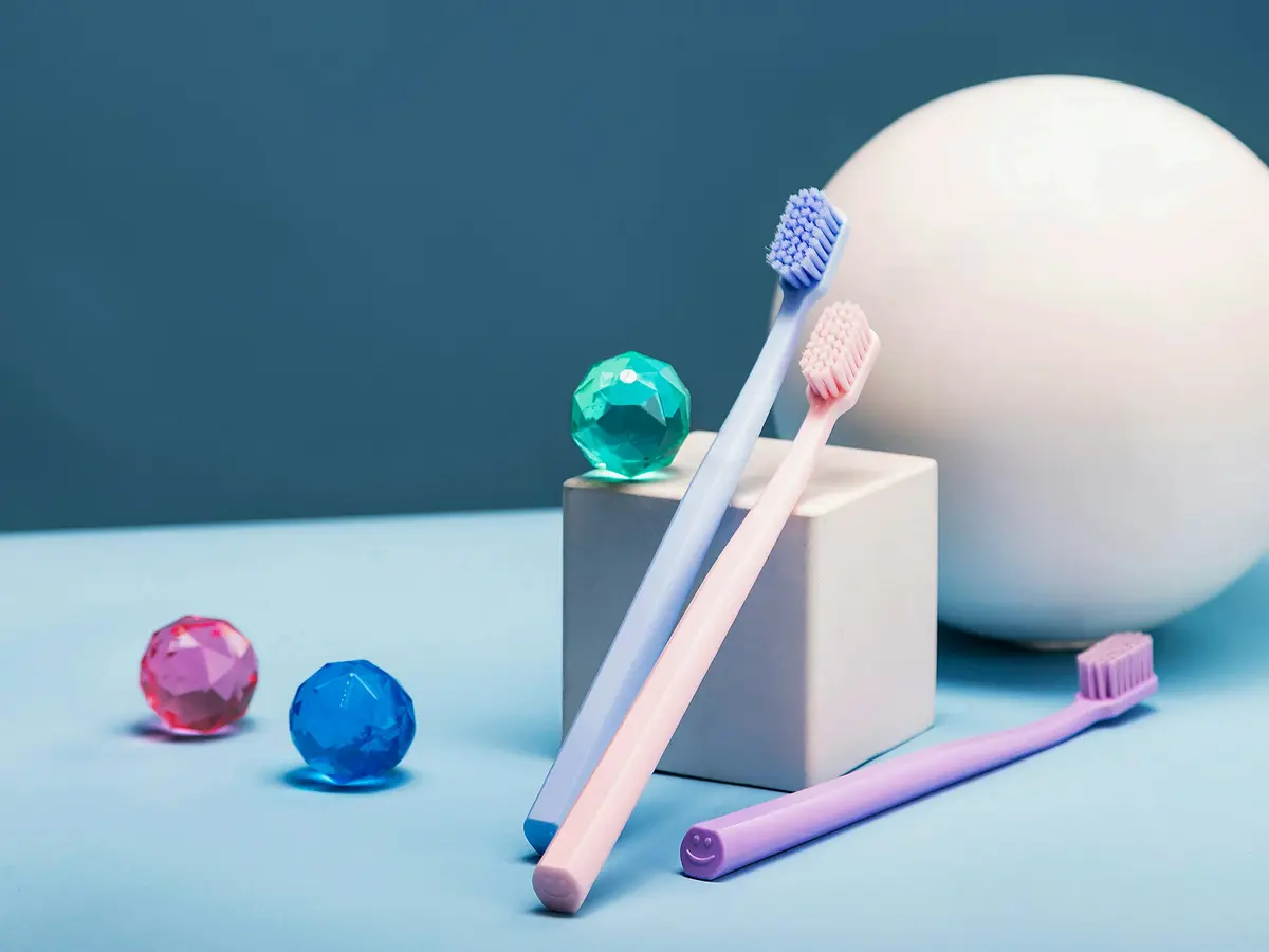 Pastel toothbrushes and small glass marbles on a blue table