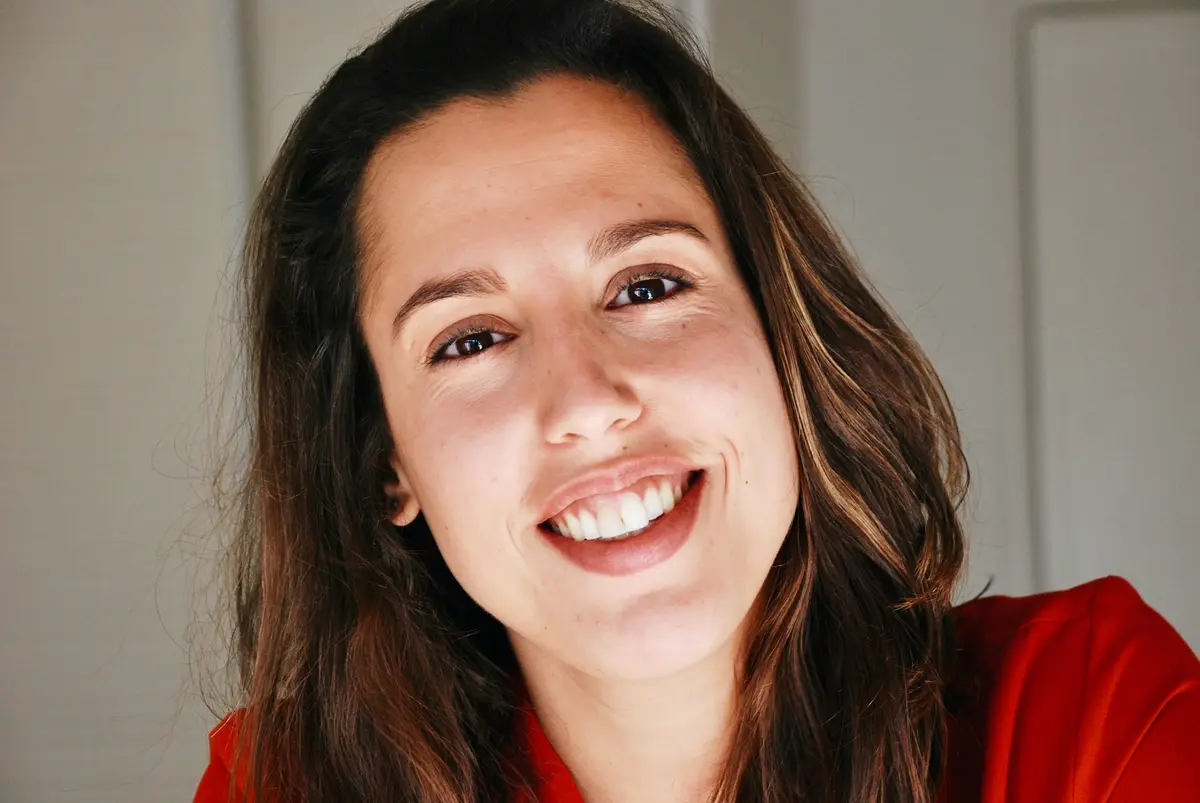 A woman in a red top smiling at the camera